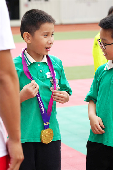 佩戴上亚运金牌后的孩子难掩兴奋，不停地和同学交流 主办方供图.jpg