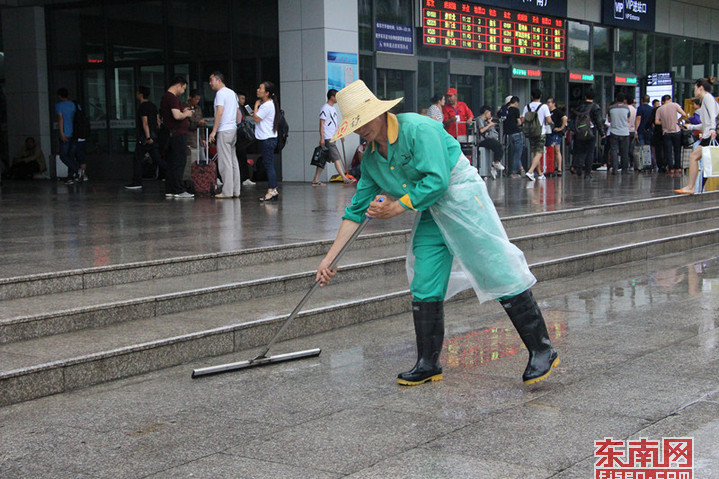 图四：福州火车站工作人员在打扫站前路面积水。.jpg