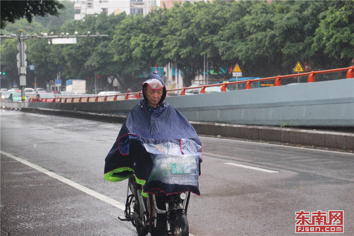 大雨磅礴冒雨前行的电动车骑手.jpg