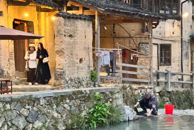 龙潭村焕新后，新潮的客人与溪边浣溪衣服的村民相遇。.jpg