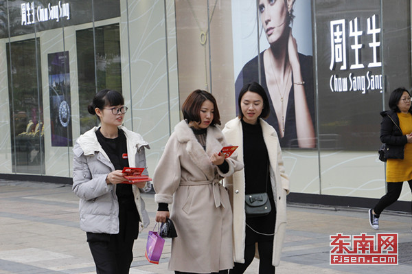 在福州某商业广场外,促销人员正给女性顾客派发广告宣传单jpg